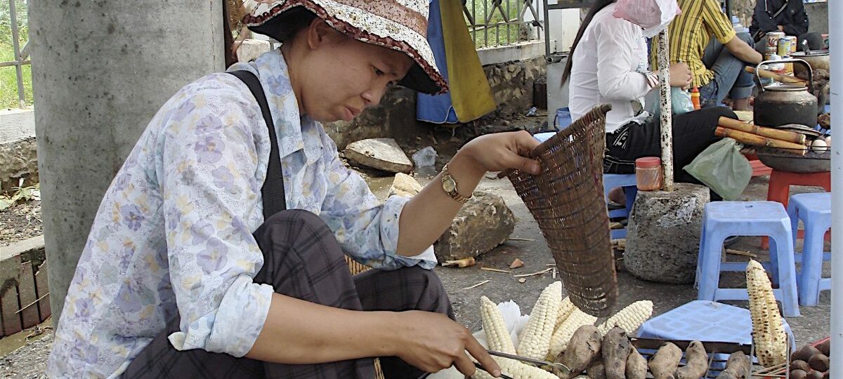 Street vendor in Sapa grilling corn, sweet potatoes and com lam bamboo sticky rice
