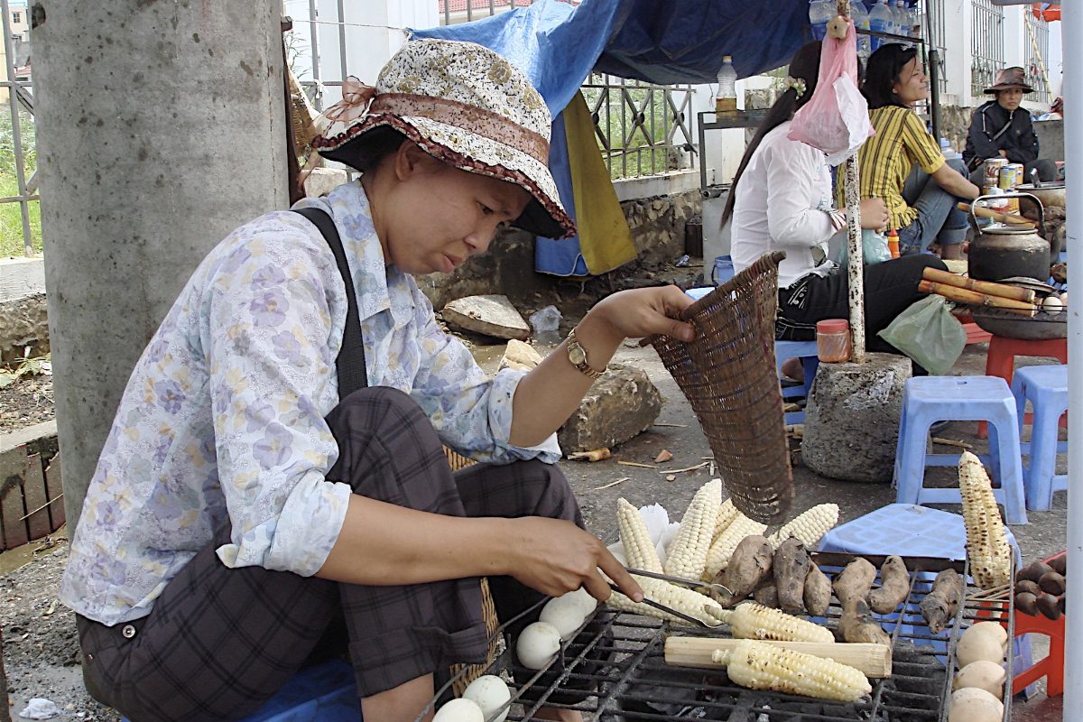 Street vendor in Sapa grilling corn, sweet potatoes and com lam bamboo sticky rice