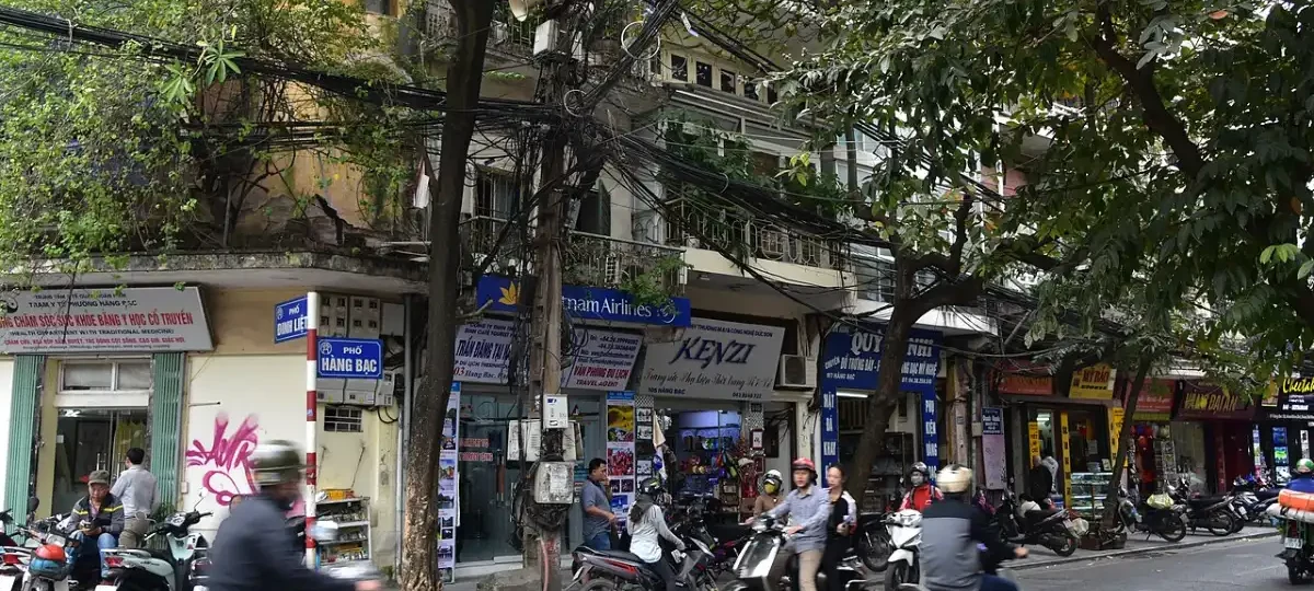 Busy street with motorbikes and shophouses in Hanoi Old Quarter