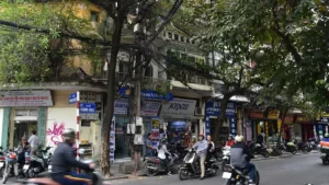 Busy street with motorbikes and shophouses in Hanoi Old Quarter