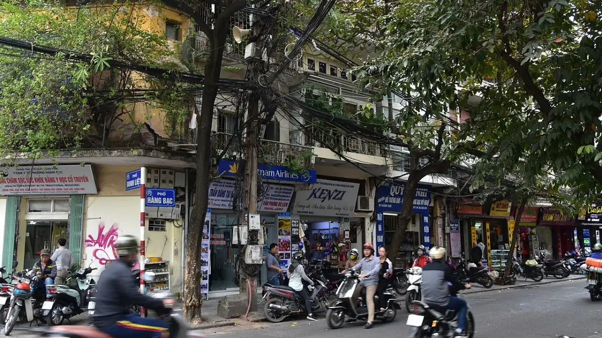 Busy street with motorbikes and shophouses in Hanoi Old Quarter